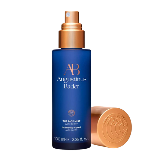 Augustinus Bader The Face Mist — sleek cobalt blue spray bottle with copper pump and cap, standing on a white background.